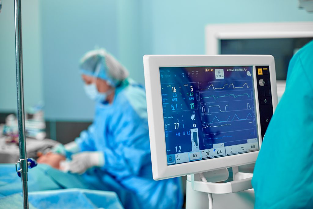 Electrocardiogram in hospital surgery operating emergency room showing patient heart rate with blur team of surgeons background